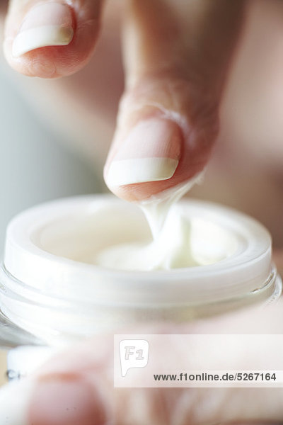 Close up of Finger Eintauchen in Topf mit Augen-Creme