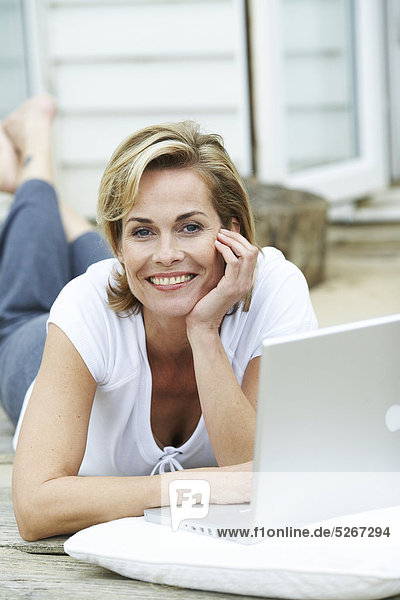 Reife Frau auf ihre Arbeiten fort ihr Laptop beachouse