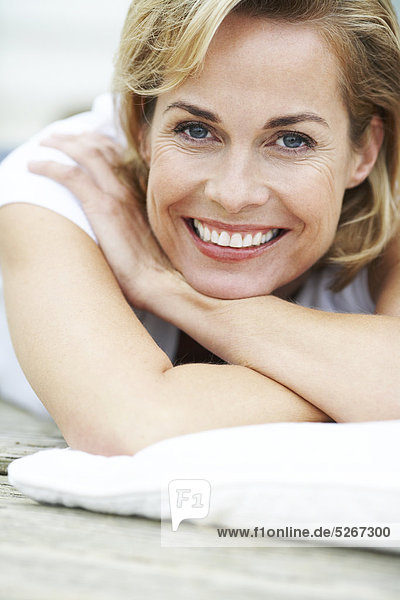 Portrait of happy Reife Woman lying on deck