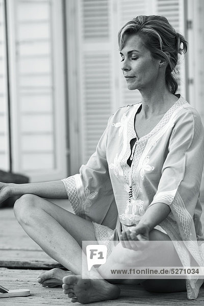 Ruhige älterer Woman doing Yoga in beachouse