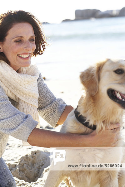 Schöne Dame mit Hund am Strand spielen