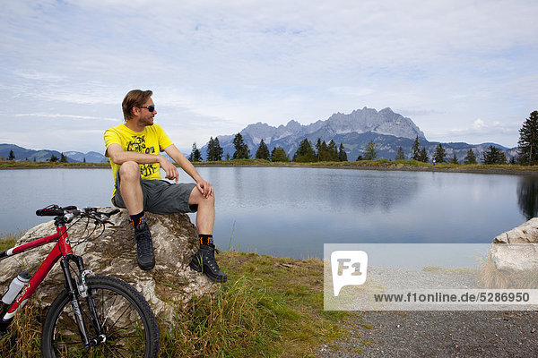 Man with mountainbike at a rock looking around