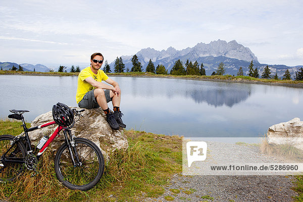 Man with mountainbike at a rock looking around