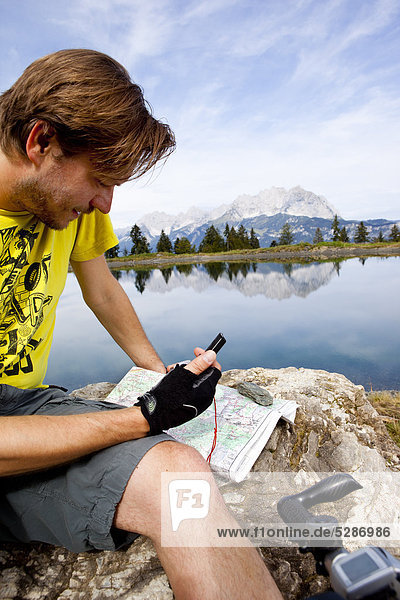 Man at a rock looking at GPS device