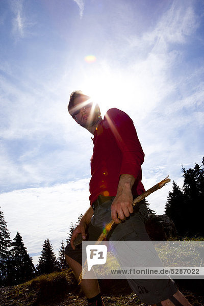 Man in red shirt holding wooden stick
