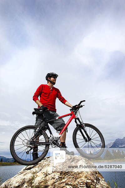 Man with mountainbike on rock peak
