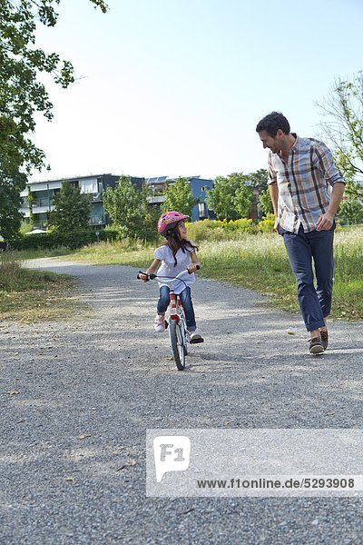 Vater rennt neben Tochter auf Fahrrad
