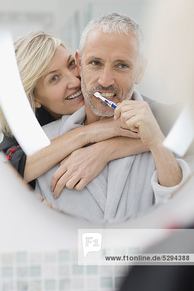 Man brushing his teeth with wife