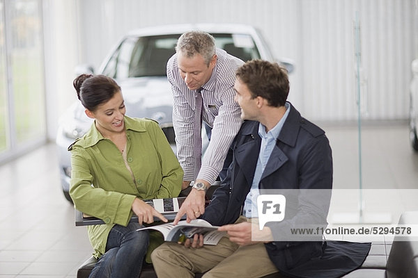 Car salesman talking with couple