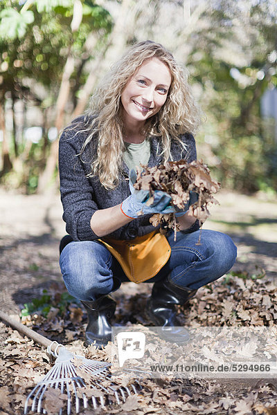 Smiling woman playing with dead leaves