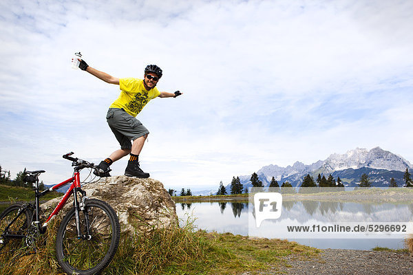 Man with mountainbike posing on rock peak
