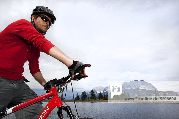 Mann mit Mountainbike an einem See