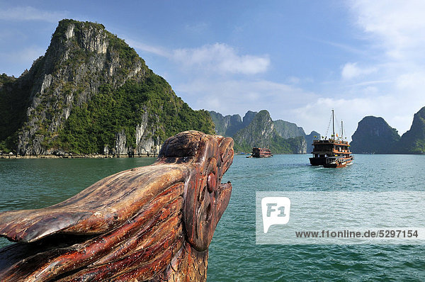 Wood carving  dragon head at the bow on a junk  Halong Bay  karst cone in the back  Vietnam  Southeast Asia