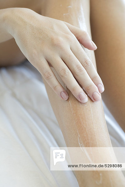 Woman moisturizing legs  cropped