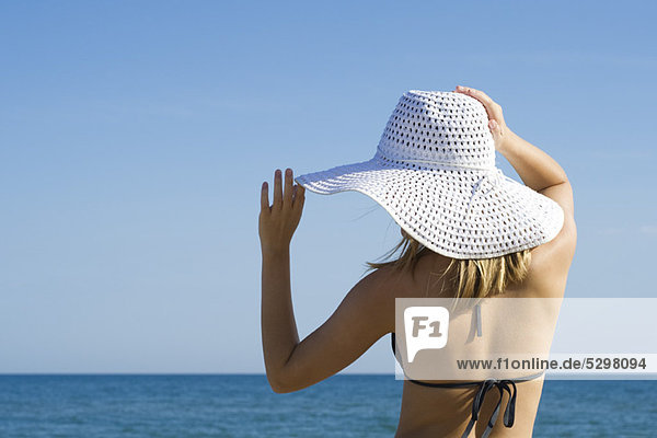Frau mit Sonnenhut am Strand  Rückansicht
