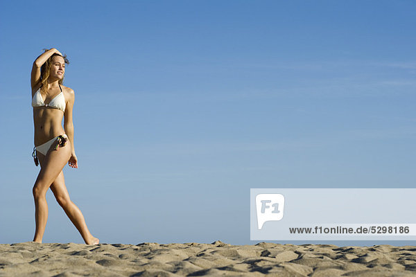 Frau im Bikini beim Spaziergang am Strand