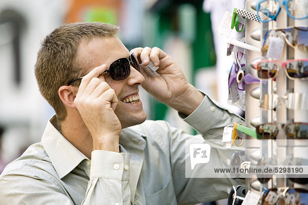 Mann probiert Sonnenbrille auf dem Straßenmarkt an