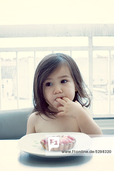 Kleines Mädchen isst Himbeertorte
