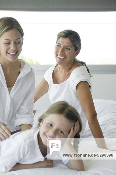 Woman relaxing on bed with daughter and granddaughter