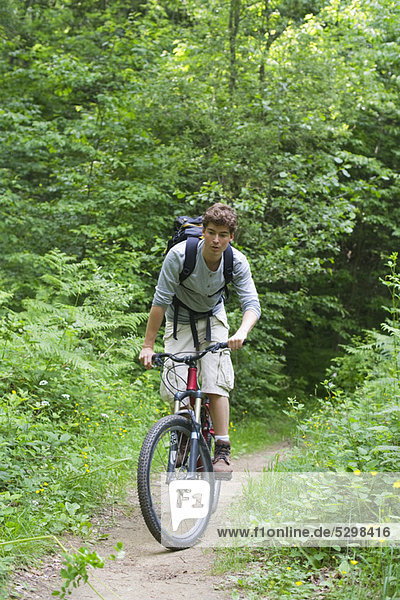 Mann fährt mit dem Fahrrad durch den Wald
