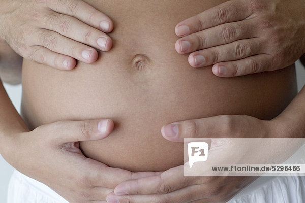 Paarhände auf dem schwangeren Bauch der Frau