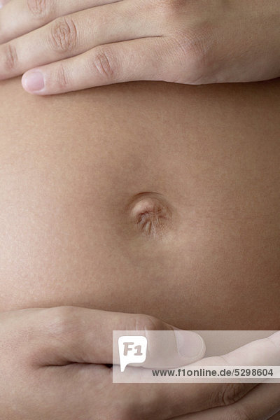 Nahaufnahme der Hände der Frau am schwangeren Bauch