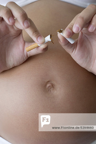 Schwangere Frau zerbricht Zigarette in zwei Hälften  abgeschnitten