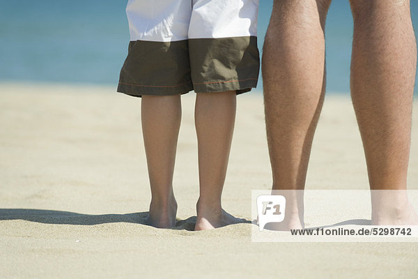 Vater und Sohn stehen zusammen am Strand  abgeschnitten