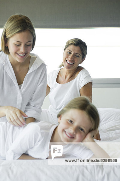 Girl relaxing on bed with her mother and grandmother