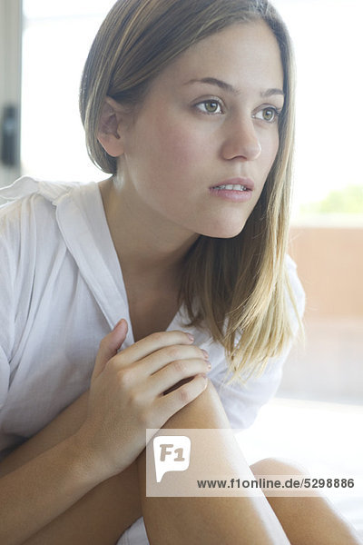 Woman touching knee  looking away in thought
