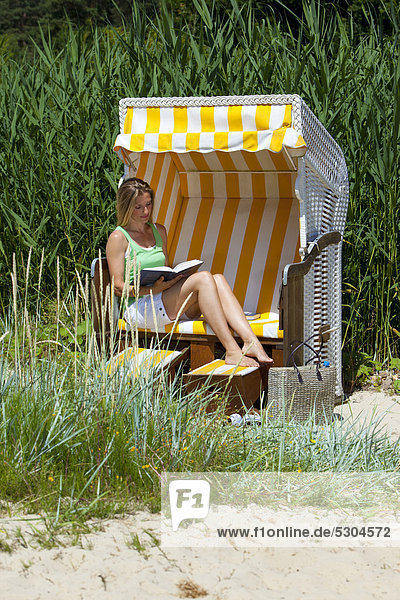 Frau im Strandkorb liest ein Buch