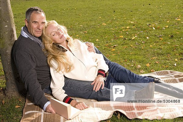 Reifes Paar sitzt auf einer Wolldecke im Park