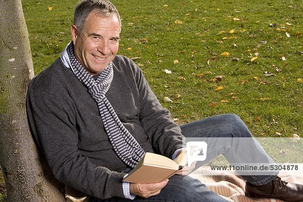 Reifer Mann liest ein Buch im Park