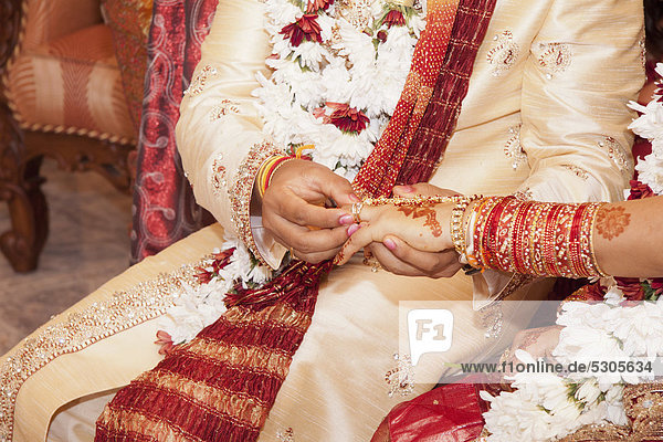 Indian groom passing wedding ring on his bride's finger
