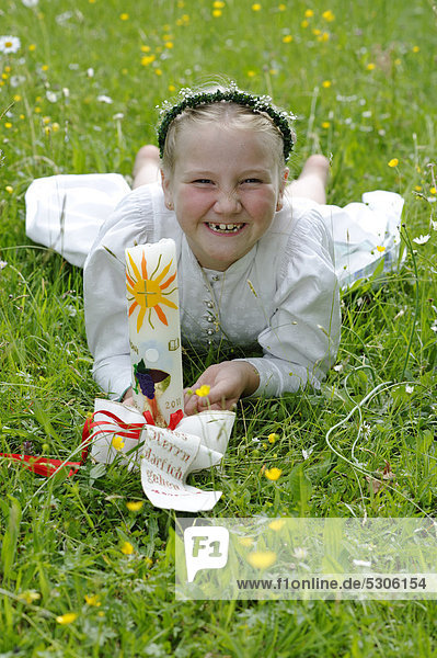 Girl lying in a meadow wearing her white First Holy Communion dress