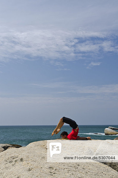 Woman in a yoga position  Salabhasana  by the sea in Kanyakumari  Tamil Nadu  India  Asia