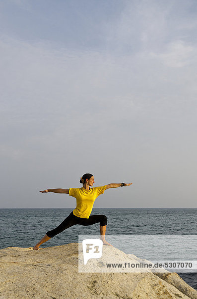 Woman in a yoga position  Virabhadrasana  by the sea in Kanyakumari  Tamil Nadu  India  Asia