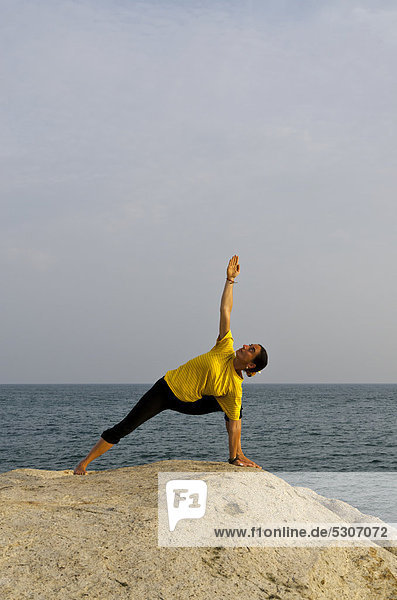 Woman in a yoga position  Utthita-Parshvakonasana  by the sea in Kanyakumari  Tamil Nadu  India  Asia