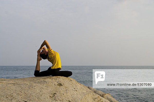 Woman in a yoga position  Kapotasana  by the sea in Kanyakumari  Tamil Nadu  India  Asia