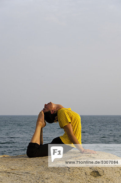 Woman in a yoga position  Bhujangasana  by the sea in Kanyakumari  Tamil Nadu  India  Asia