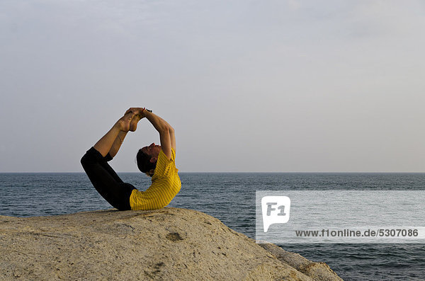 Woman in a yoga position  Dhanurasana  by the sea in Kanyakumari  Tamil Nadu  India  Asia