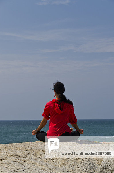 Woman in a yoga position  Padmasana  by the sea in Kanyakumari  Tamil Nadu  India  Asia