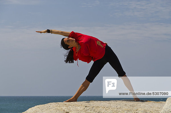 Woman in a yoga position  Trikonasana  by the sea in Kanyakumari  Tamil Nadu  India  Asia
