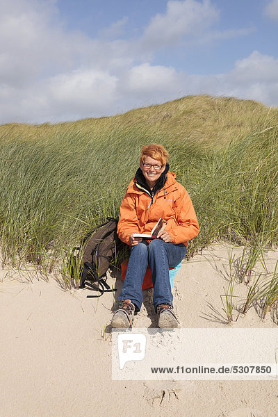 Woman sitting in the dunes on the island of Amrum  North Frisian Island  Schleswig-Holstein  Germany  Europe