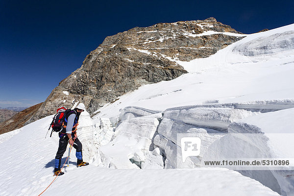 Climber passing through the glacial landscape while descending Piz Palue  Grisons  Switzerland  Europe