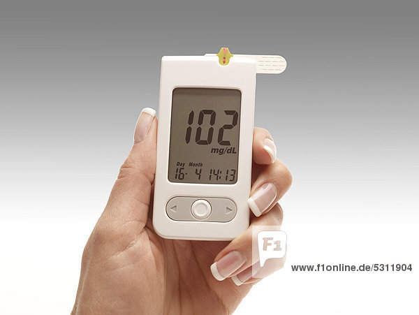 Hand holding a blood glucose meter
