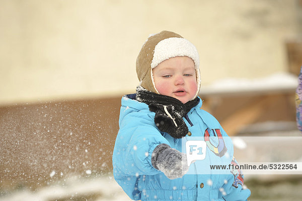 Junge  2 Jahre  mit Schneeanzug  spielt im Schnee