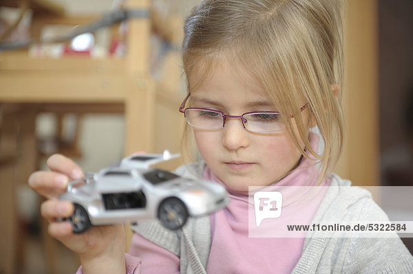 4 jähriges Mädchen spielt mit einem Spielzeugauto
