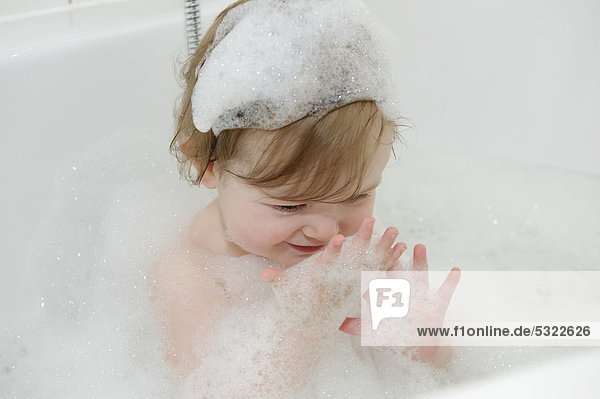 Mädchen  15 Monate  spielt mit Schaum in der Badewanne