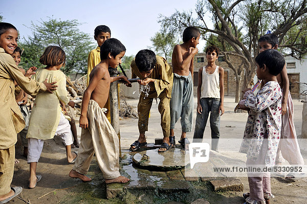 Children drinking water from the pump of a well  village of Moza Sabgogat near Muzaffaragarh  Punjab  Pakistan  Asia